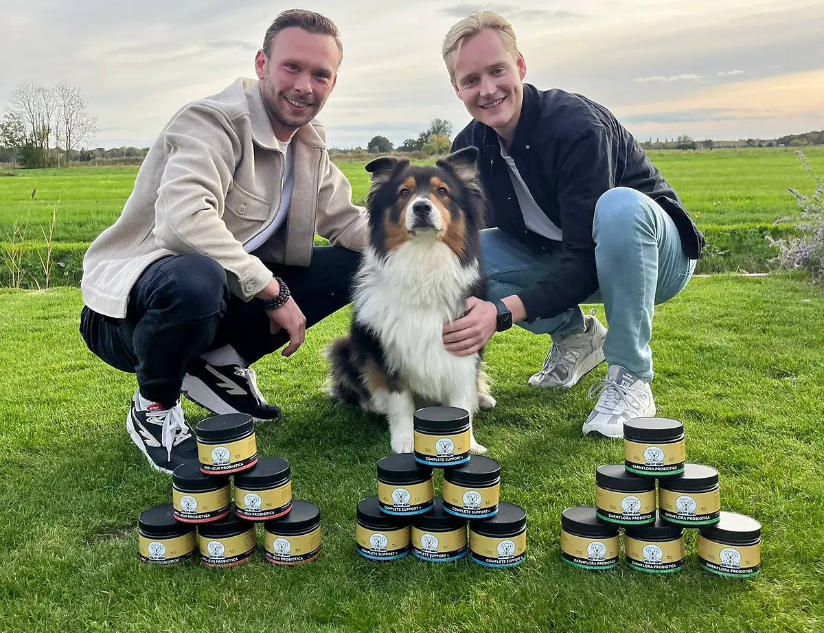 Joey van den Brink en zijn compagnon met hun hond en de Healthy Heads-producten in een weiland